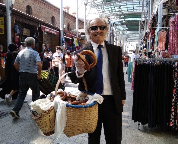 Is insani gibi giyinip çarsida sepetle simit satiyor